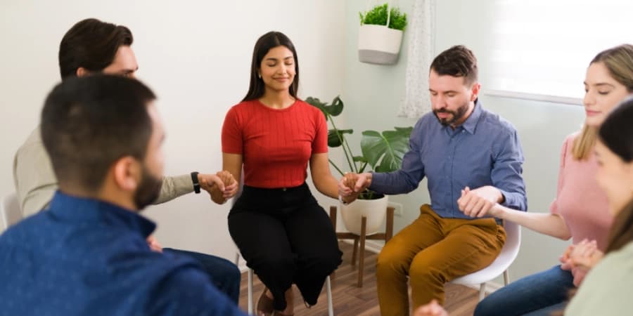 9 Ways AA Meetings Near Me Help You Live Alcohol-Free A group of friends in an AA meeting holding hands in a circle