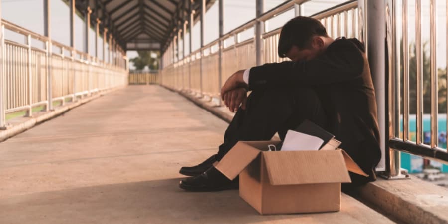 Career Tips for Staying Sober at Work A man seated out on the ground, depressed after losing his career to aloholism