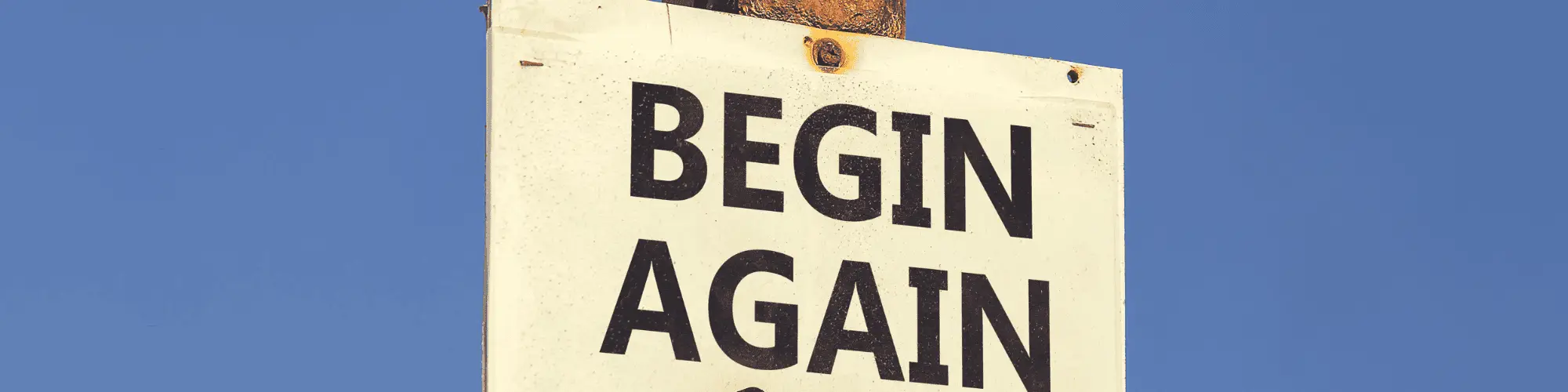 How AA Meetings Help Rebuild Lives After Alcohol Addiction A sign that says "begin again"