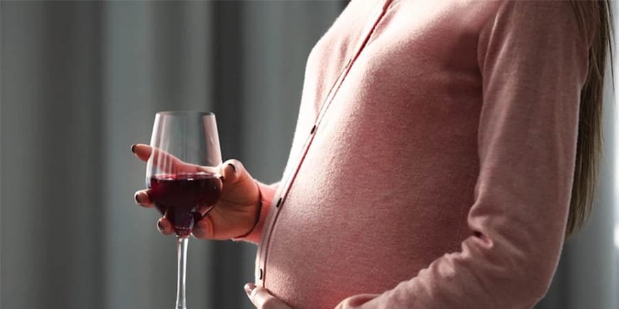 Why No Alcohol Intake is Safe When You’re Pregnant A mother carrying a glass of wine